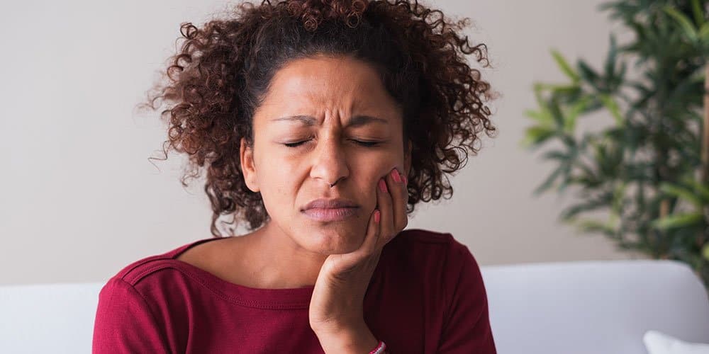 Woman with gum disease holding sore jaw