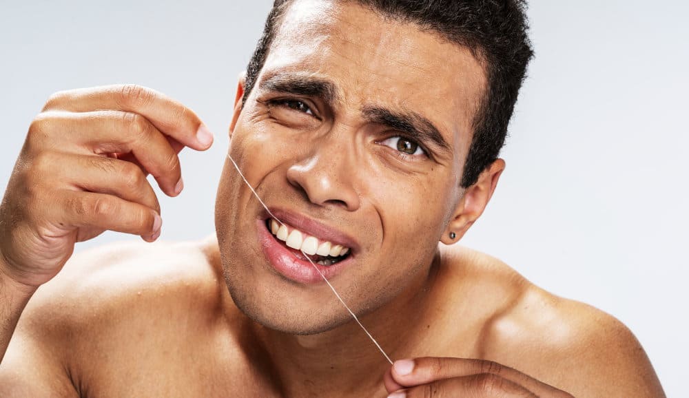 Unhappy man flossing